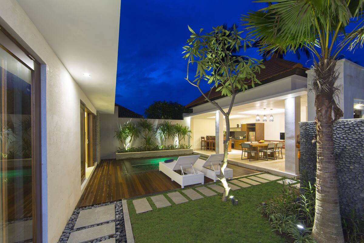 Ein modernes Haus mit Pool, Sitzgelegenheit im Freien und einem gepflegten Garten.