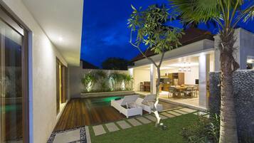 Una casa moderna con piscina, mobiliario de exterior y un jardín cuidado.