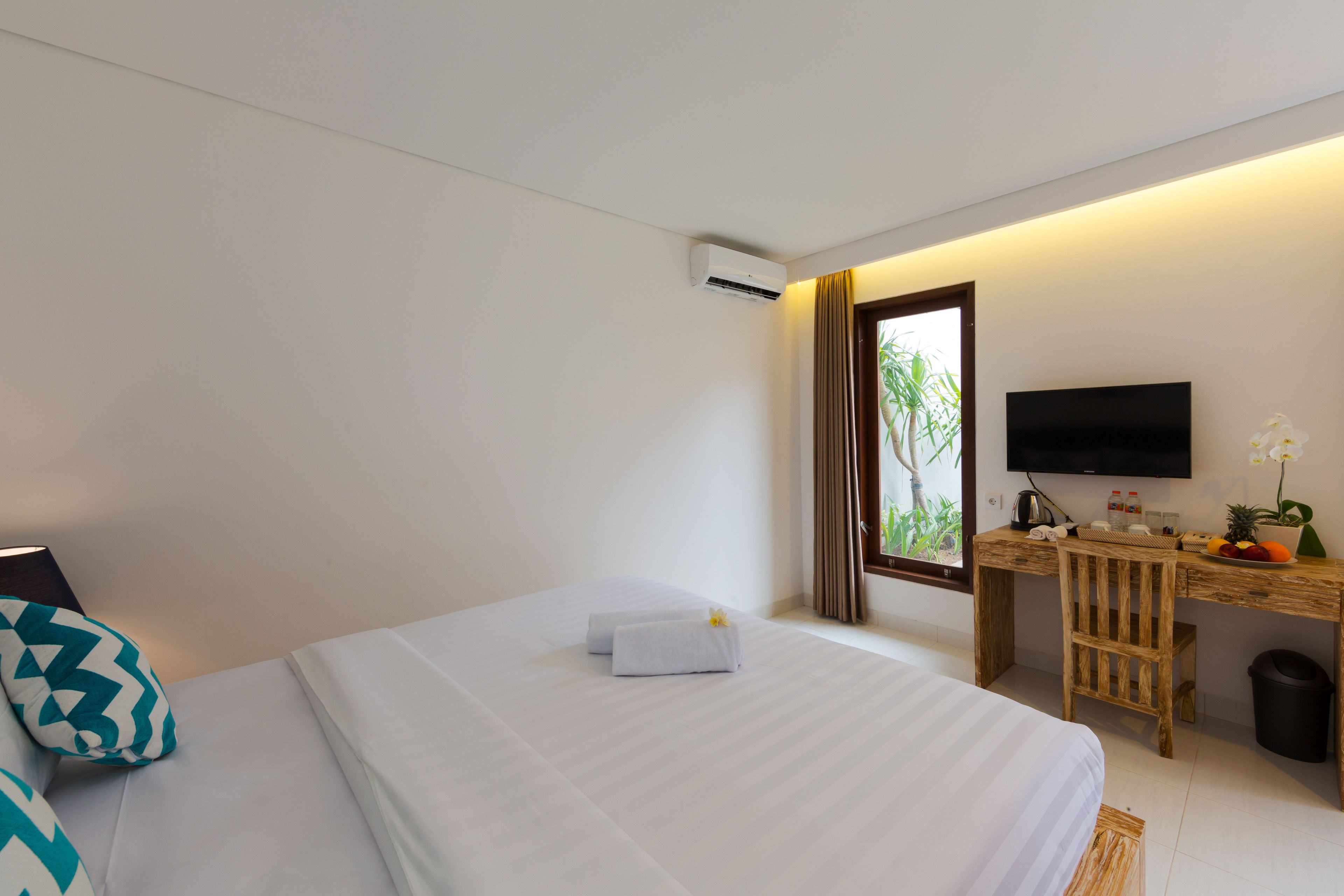 Una habitación de hotel con cama, escritorio, televisor y ventana con cortinas.