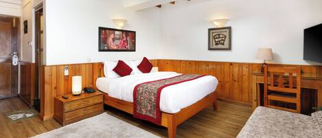 A bedroom with a wooden bed, bedside tables, a TV, and a desk.