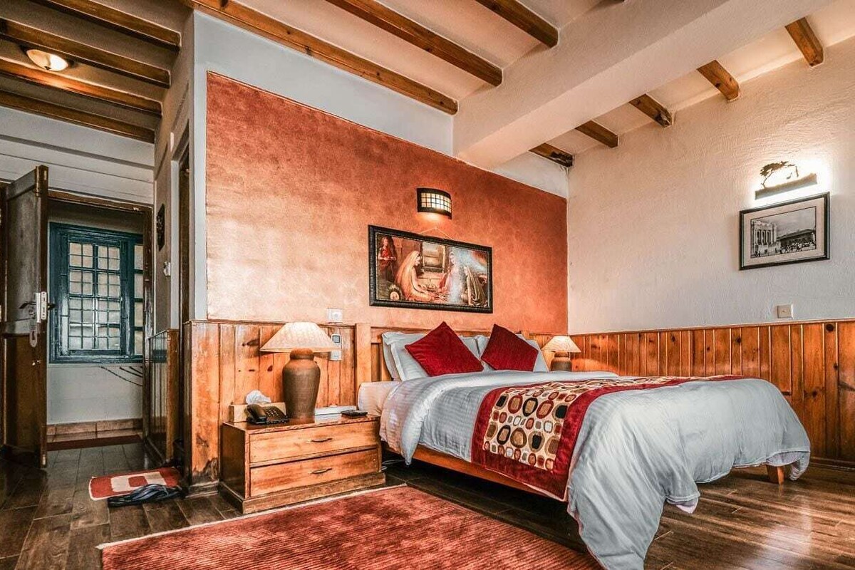 Un dormitorio con cama de madera, mesitas de noche, alfombra roja y una lámpara de pared.