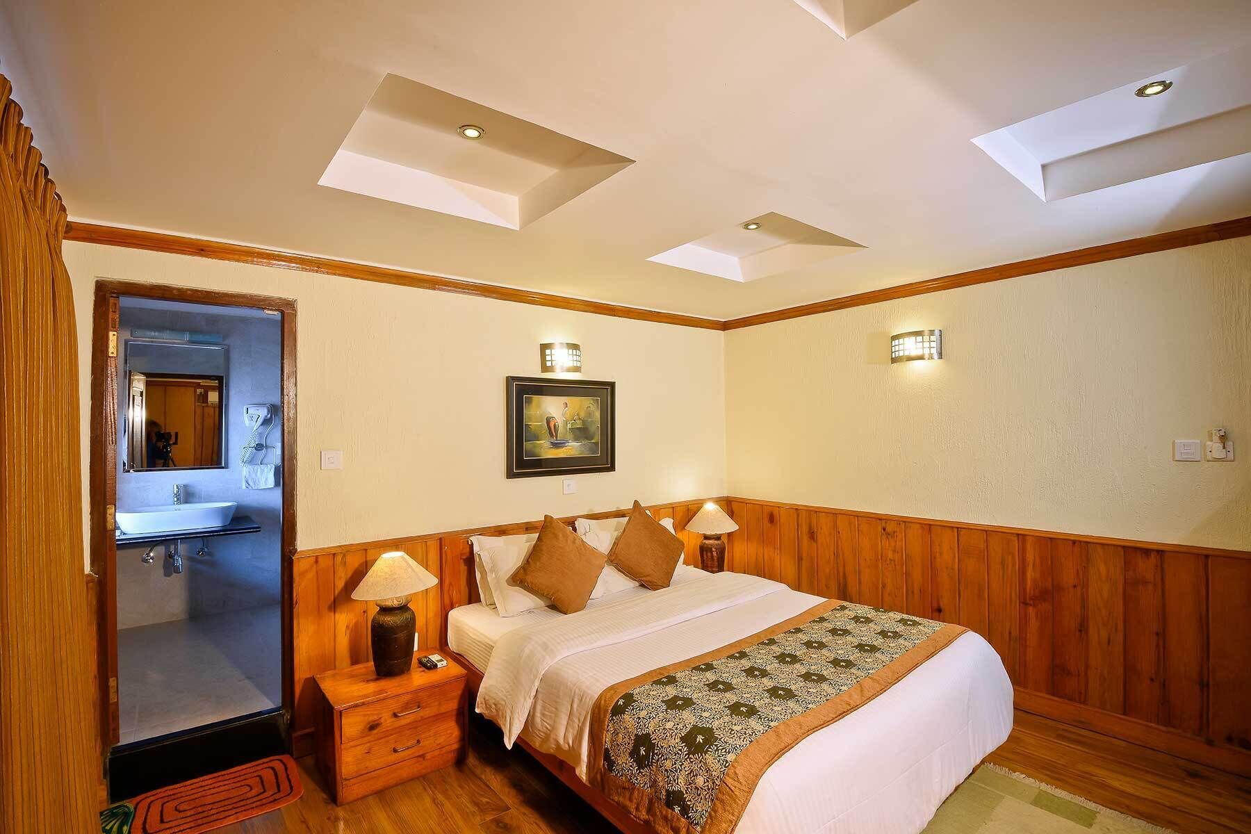 A bedroom with a bed, nightstands, a mirror, a painting, and a wooden ceiling.