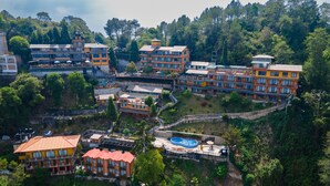 Un hôtel à plusieurs étages doté de balcons, d’une piscine et entouré d’une végétation luxuriante.
