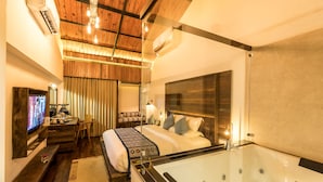Une chambre d’hôtel avec un grand lit, un coin salon avec un téléviseur, un bureau et une baignoire.