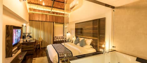 Una habitación de hotel con una cama grande, una zona de estar con televisor, un escritorio y una bañera.