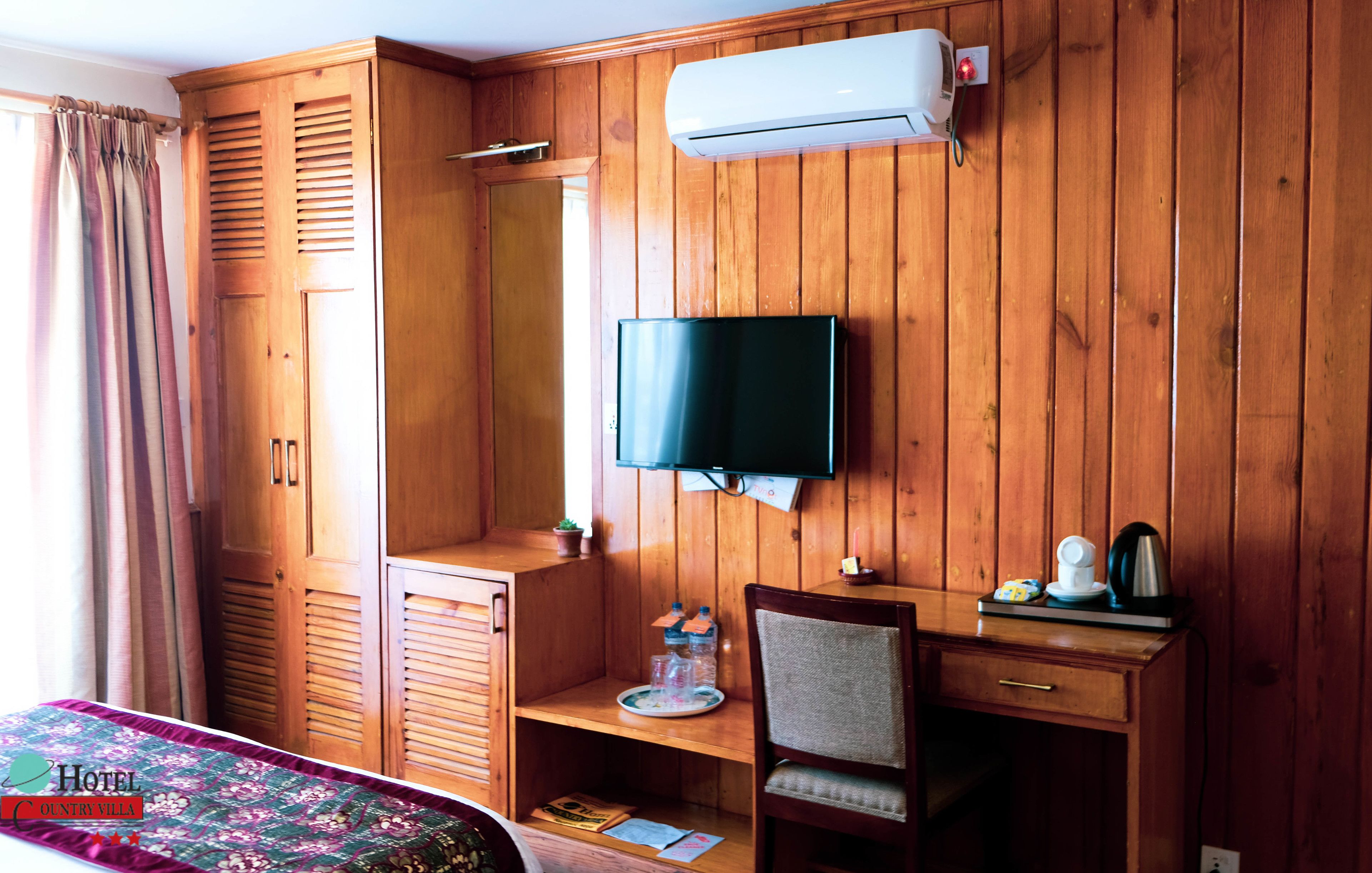 A wooden-paneled room with a bed, a TV, a desk, and a chair.