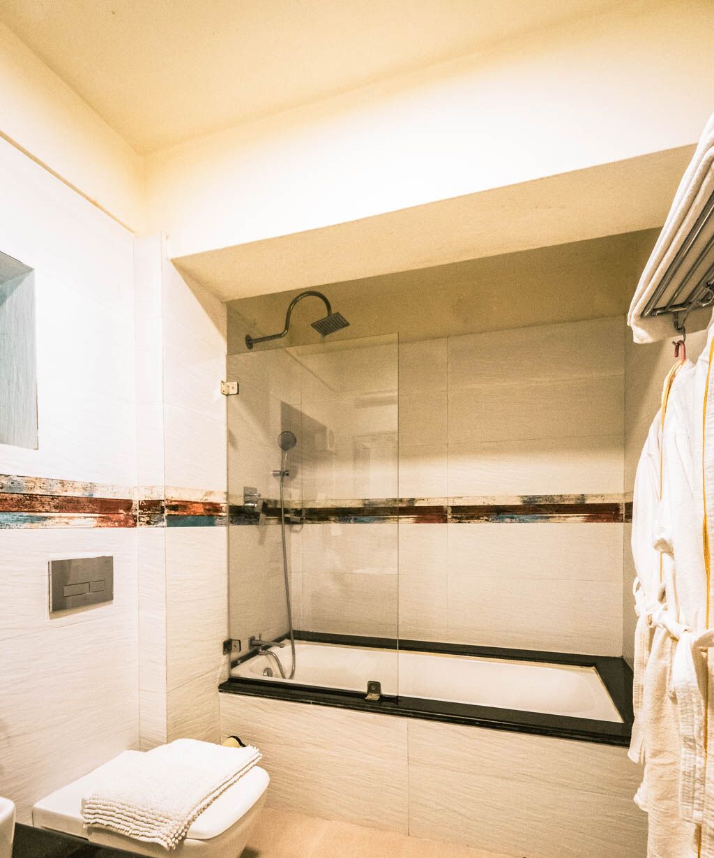 A bathroom with a glass-enclosed shower, a toilet, and a towel rack.