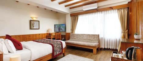 Habitación de hotel con una cama de madera, un sofá, un escritorio y un televisor.