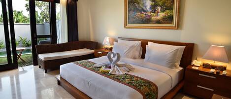 A hotel room with a large bed, a wooden nightstand, a wicker chair, and a painting on the wall.