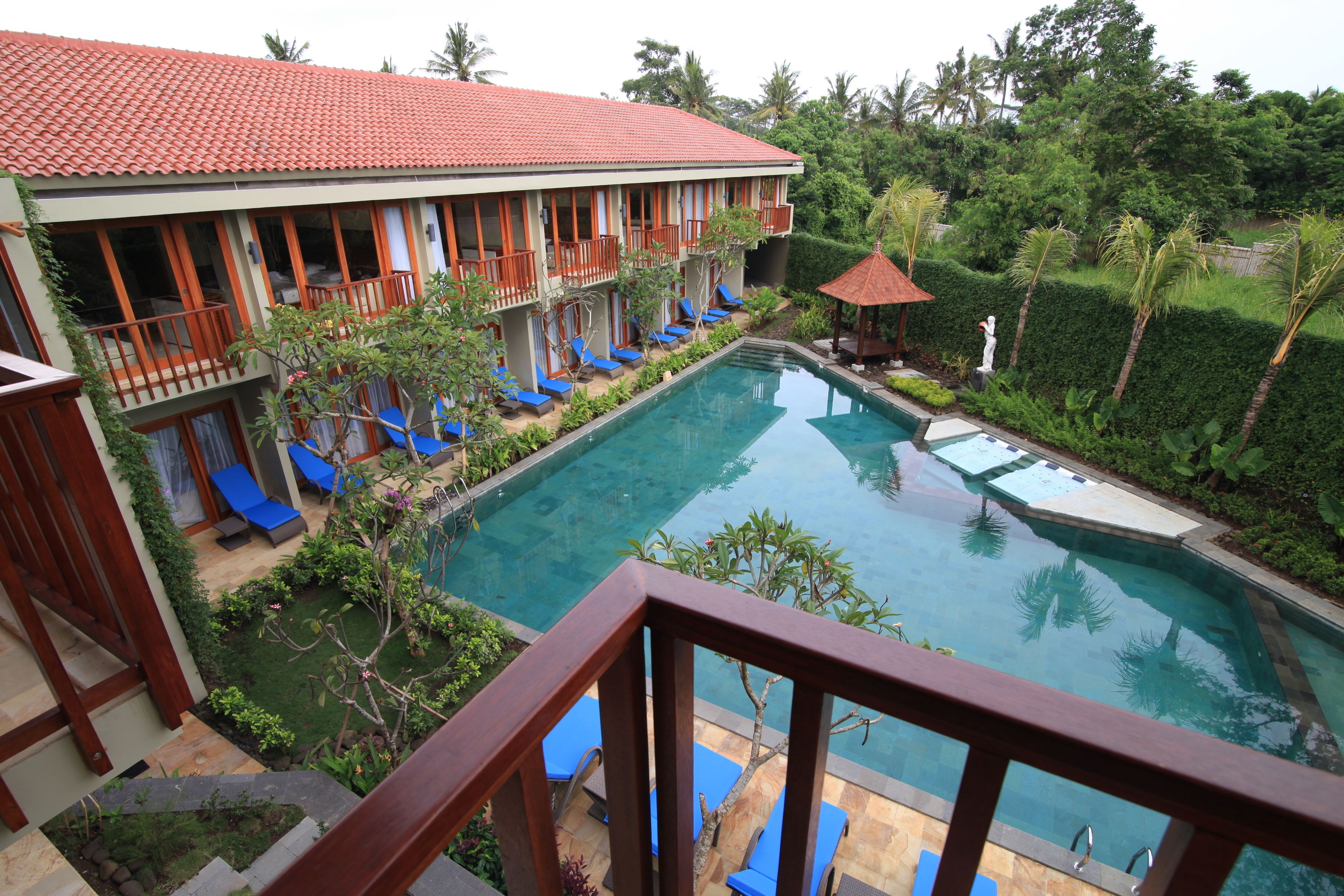 A hotel with a swimming pool, multiple balconies, and lounge chairs.