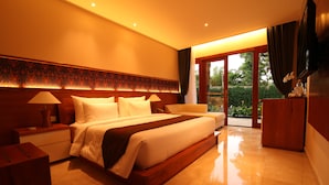 A spacious bedroom with a large bed, a nightstand, a dresser, and a television. - Ubud Wana Resort (Ubud)