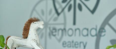 A white horse sculpture in front of a wall with a logo and the text "lemonade eatery".
