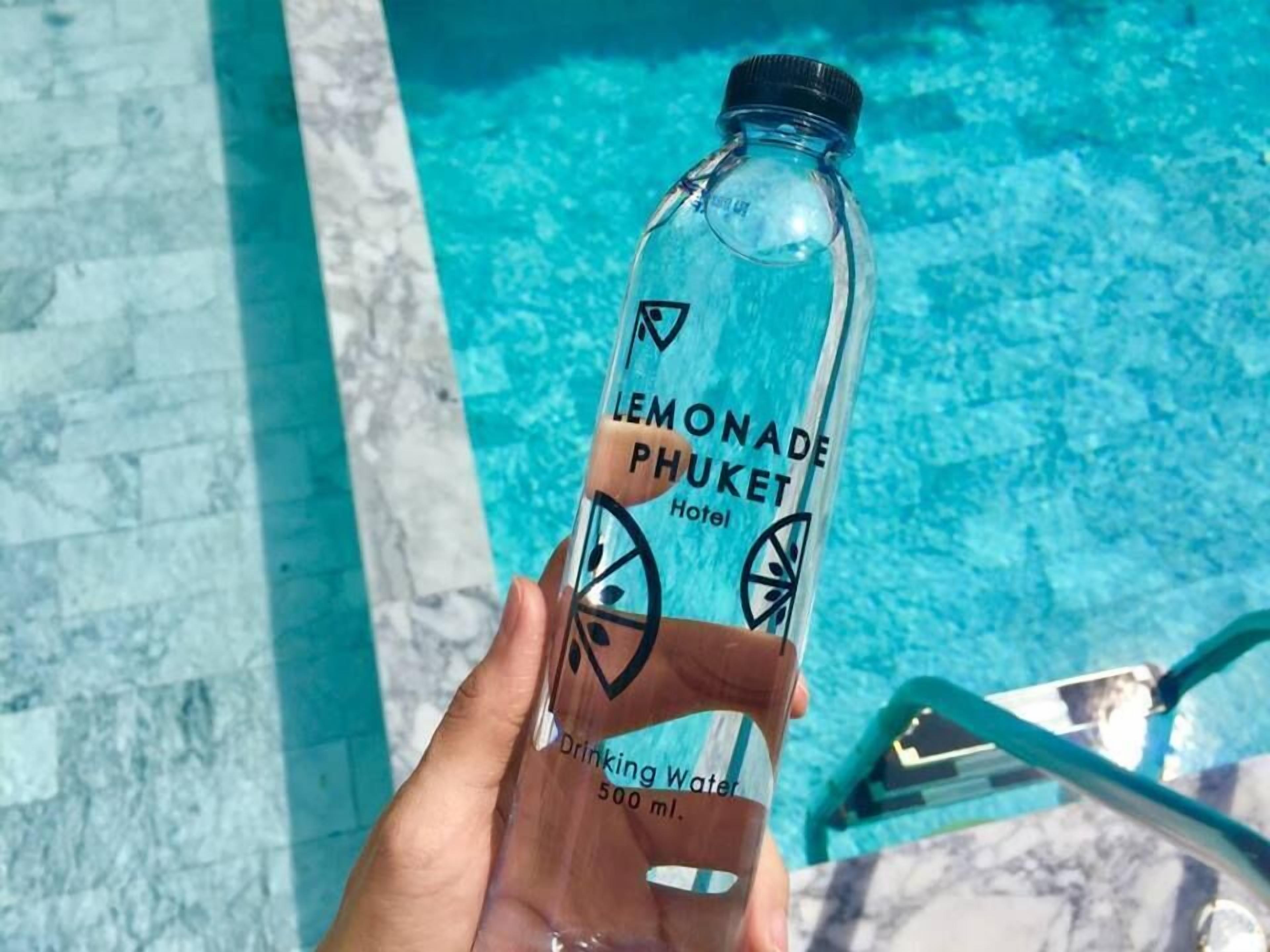 A hand holding a bottle labeled 'Lemonade Phuket Hotel' with a capacity of 500 ml.