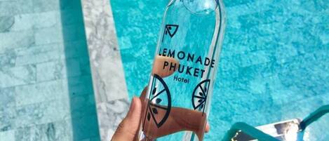 A hand holding a bottle labeled 'Lemonade Phuket Hotel' with a capacity of 500 ml.