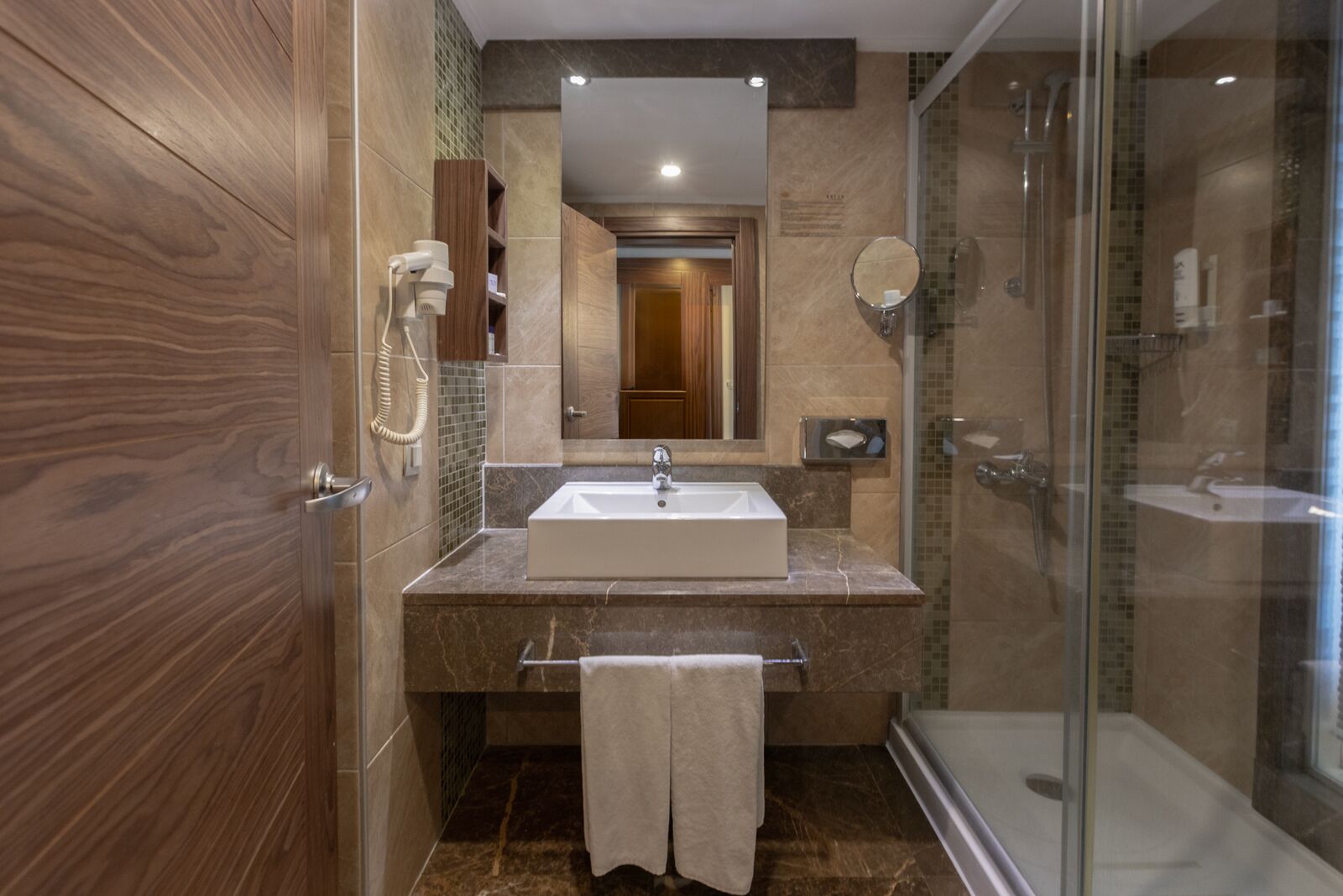 A modern bathroom with a large mirror, a sink, and a shower.