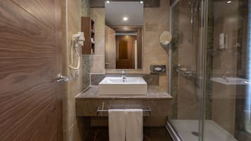 A modern bathroom with a large mirror, a sink, and a shower.