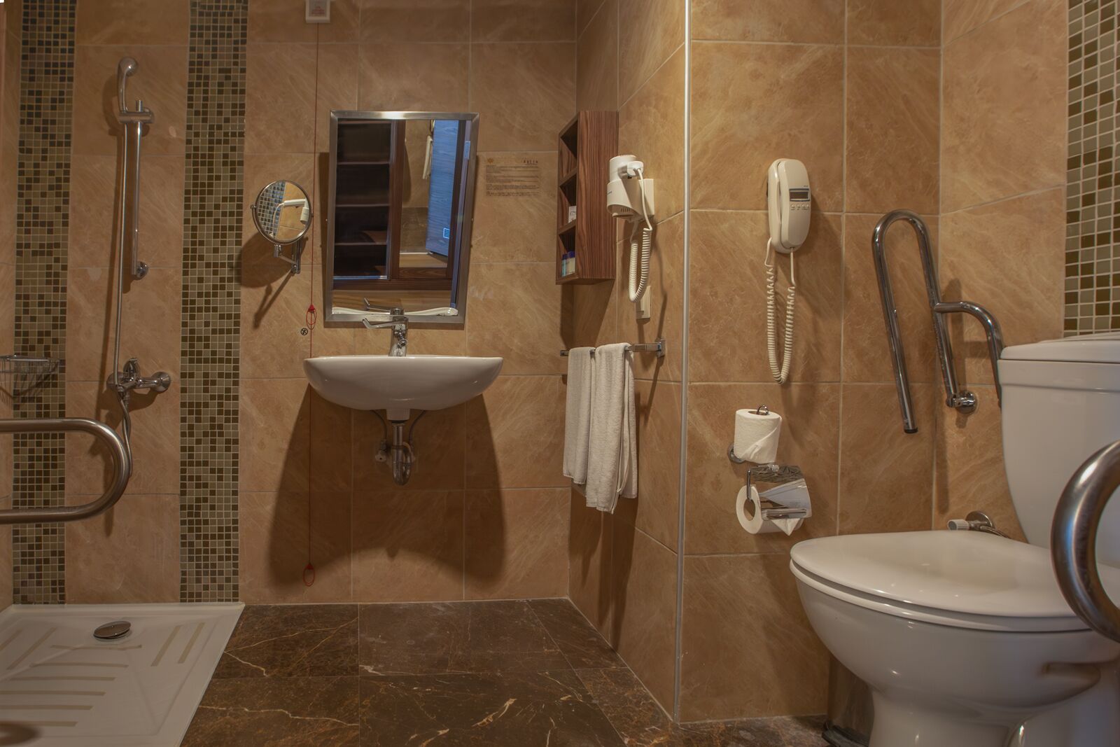 A bathroom with a sink, mirror, toilet, and shower.