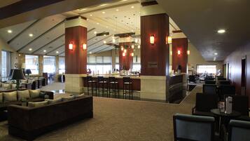 A hotel lobby with a bar area, seating arrangements, and a patterned carpet.