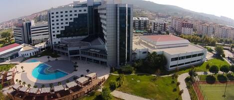 A modern building with a central courtyard, a swimming pool, and surrounding greenery.