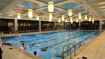 An indoor swimming pool with multiple lanes, overhead lighting, and a tiled floor.