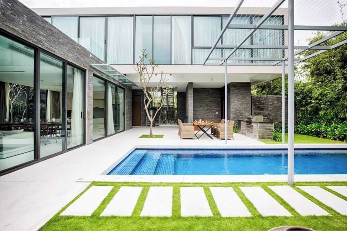 Une maison moderne dotée d’une piscine, de portes vitrées et d’un espace patio.