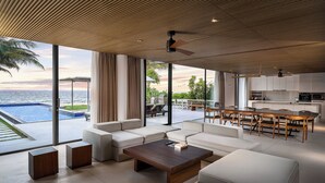 A modern living room with a view of the ocean, a pool, and a kitchen area. - Naman Retreat (Da Nang)