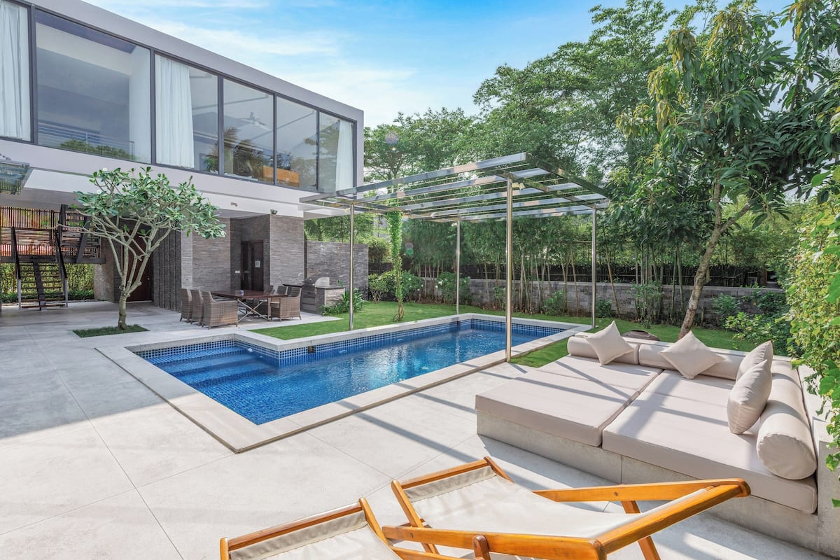 Une maison moderne dotée d’une piscine, d’un espace salon extérieur et d’une pergola.