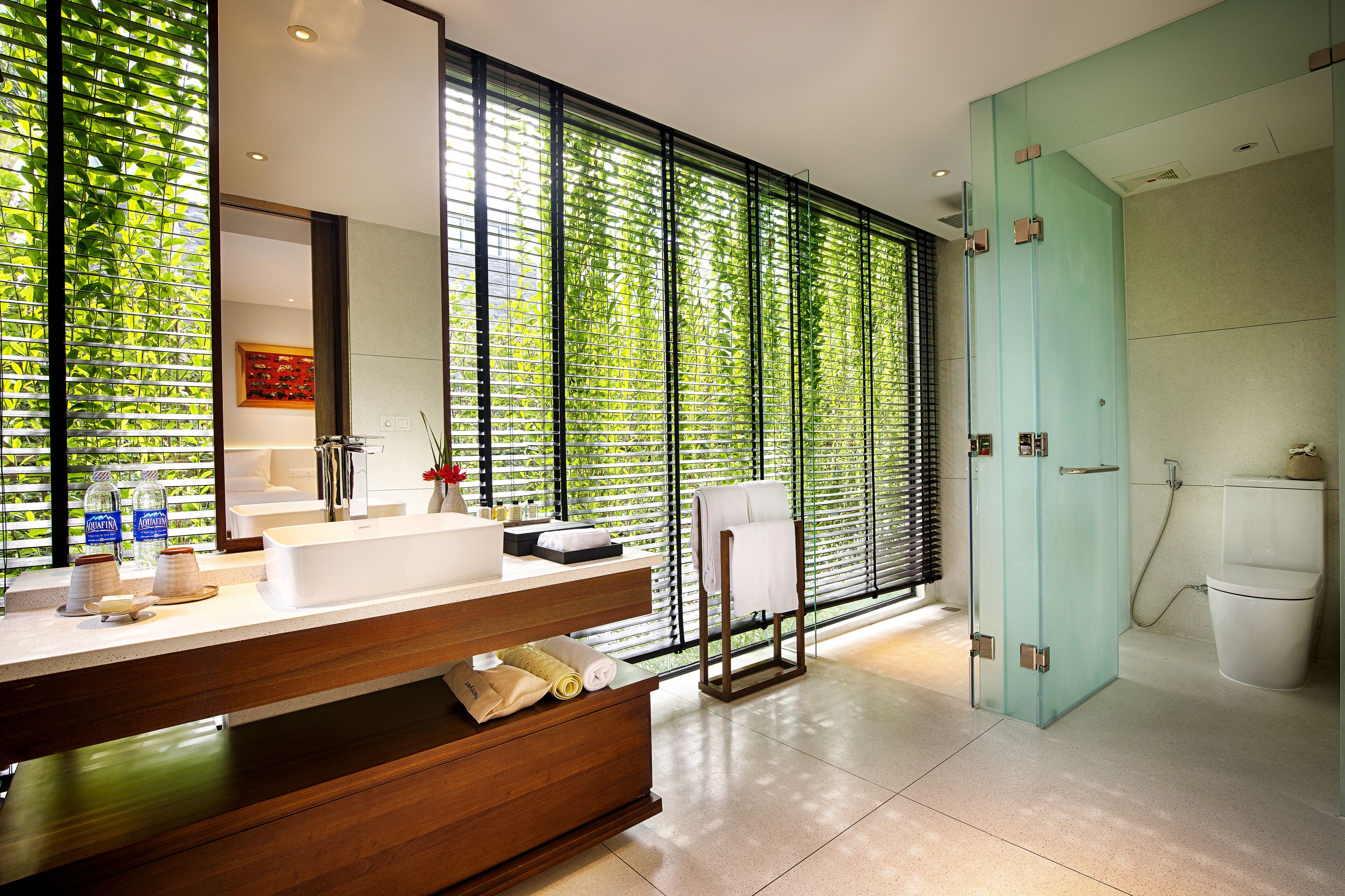 A modern bathroom with a large mirror, a wooden vanity, and a glass shower enclosure.