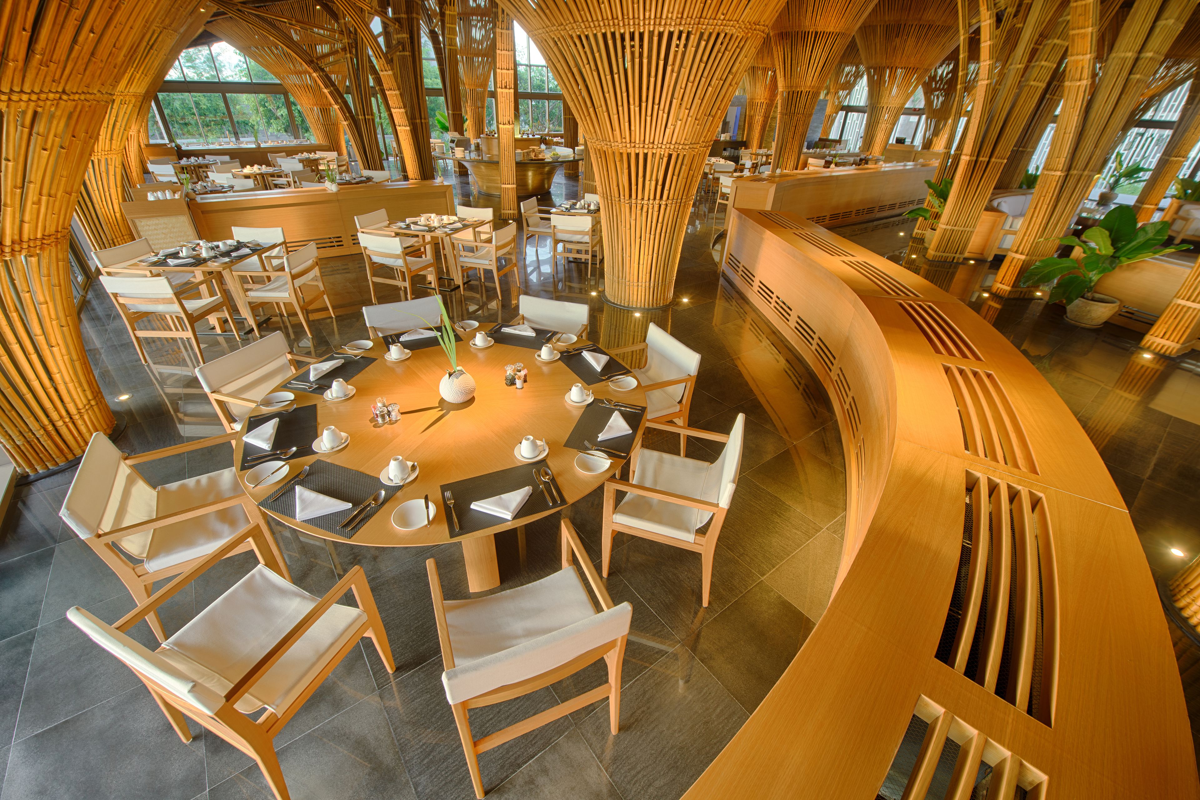 A restaurant with round tables, wooden chairs, and bamboo decor.