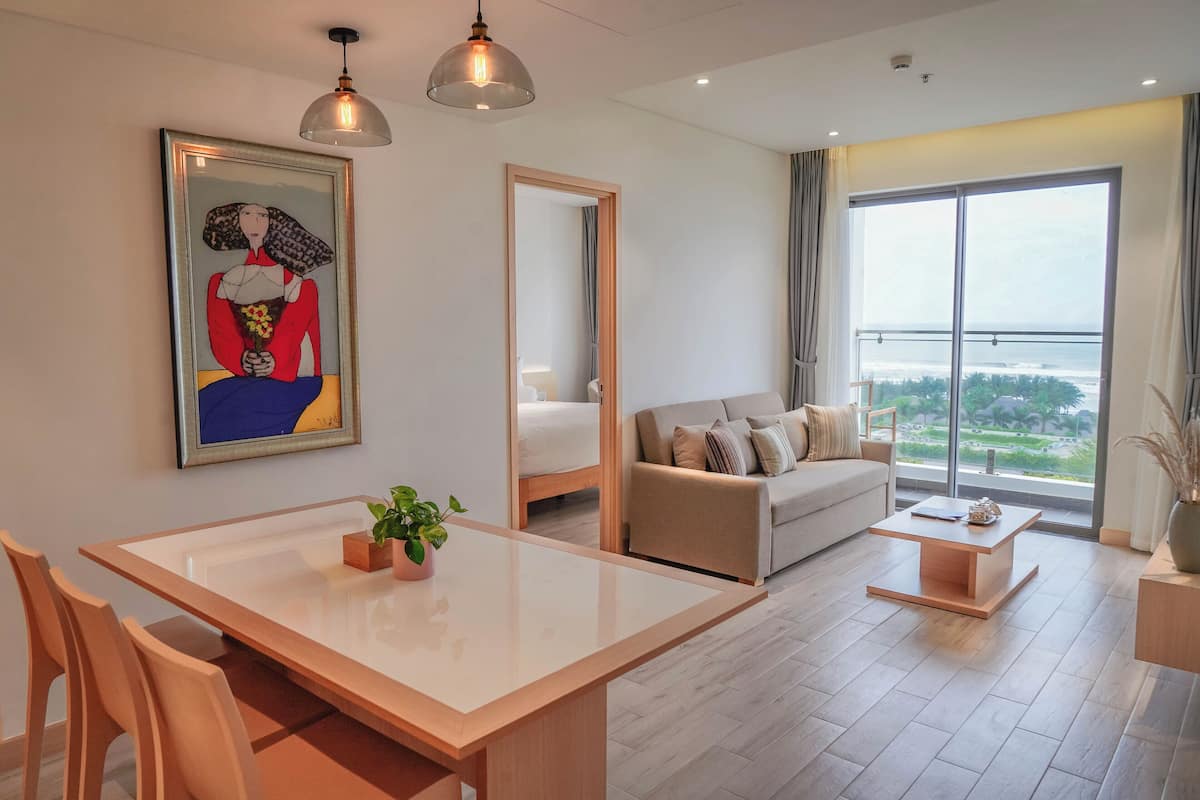 Un salon moderne comprenant une table à manger, un canapé et de grandes fenêtres donnant sur un paysage.