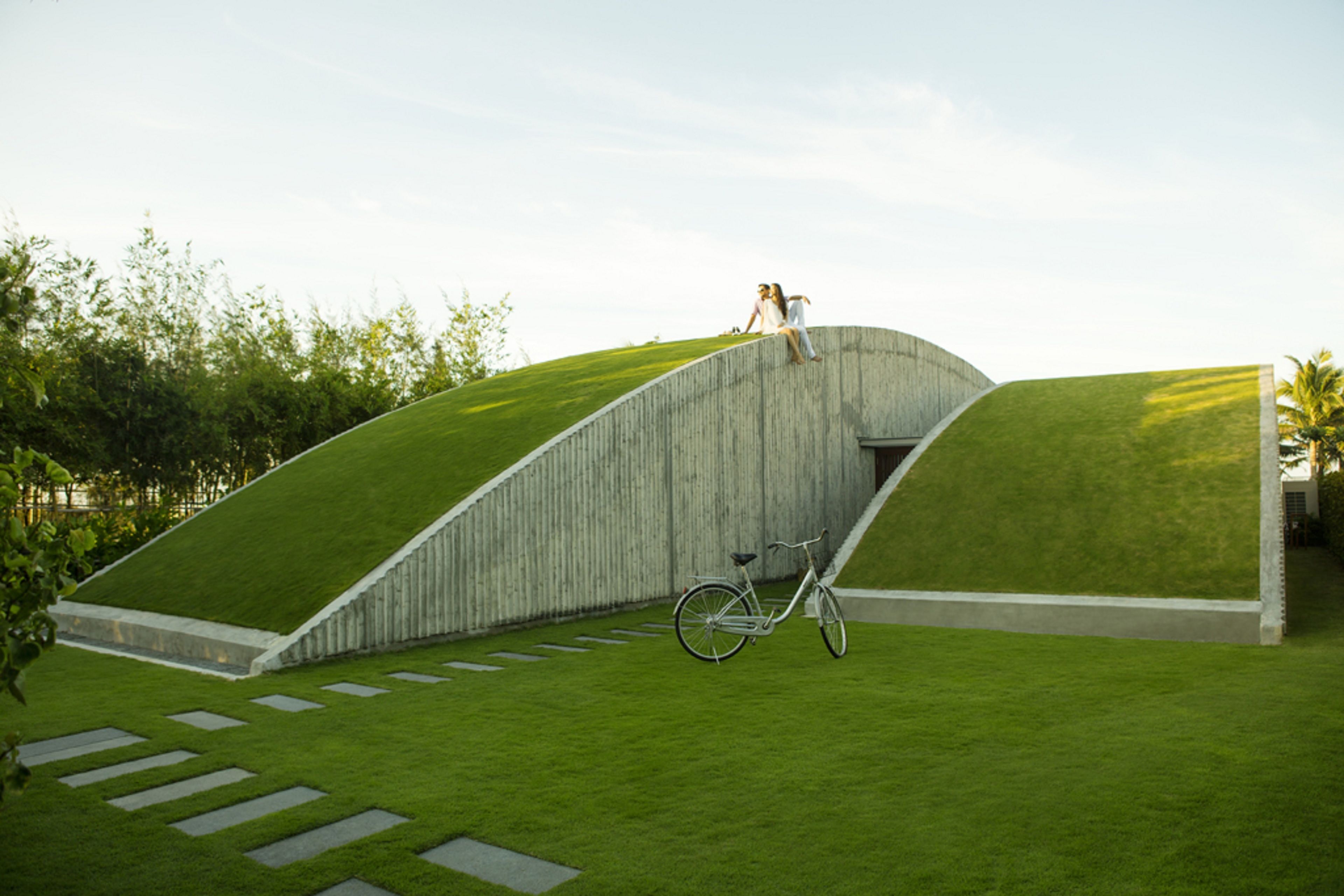 Un bâtiment moderne doté d’un toit incurvé et d’une pente couverte d’herbe.