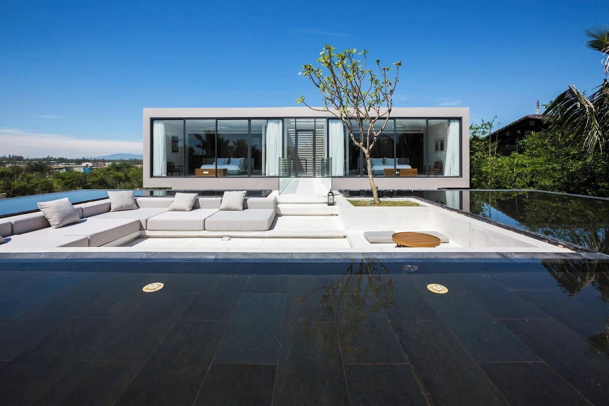 Une maison moderne dotée d’un grand espace de vie extérieur, d’une piscine et d’une vue sur le paysage environnant.