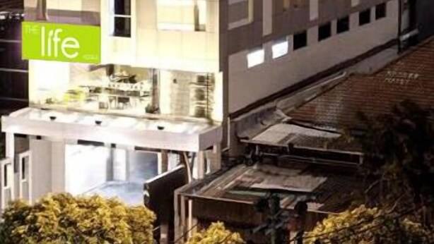 A multi-story building with a modern architectural design, featuring a mix of rectangular and square windows. - The Life Hotels (Surabaya)