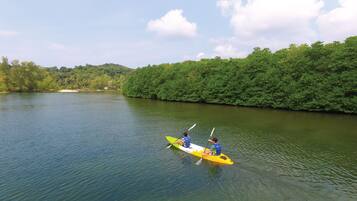 A river with a kayak and two people paddling.