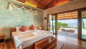 A spacious bedroom with a large bed, a wooden bench, and a view of the beach through a glass door. - Tinkerbell Resort (Ko Kood)