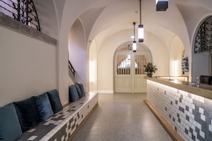 A reception area with a check-in counter, a bench with cushions, and a tiled floor.