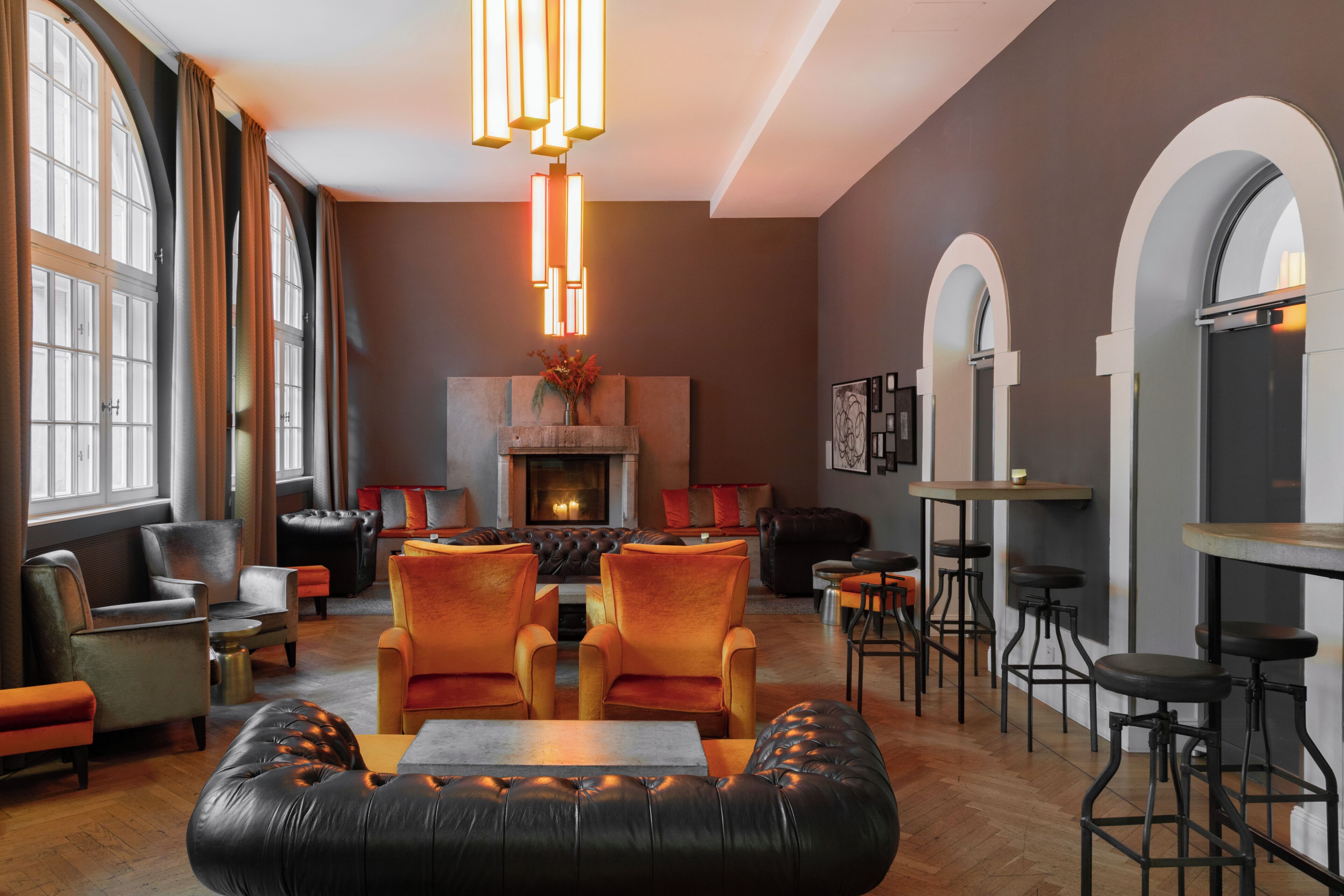 A spacious lounge area with leather seating, a fireplace, and a modern light fixture.