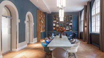 A modern dining room with a long table, blue chairs, and a central vase of flowers.
