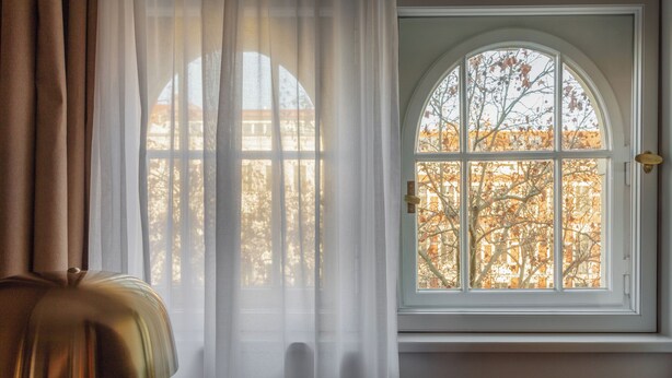 A room with a large arched window, a lamp, and sheer curtains. - Hotel Oderberger Berlin (Berlin)