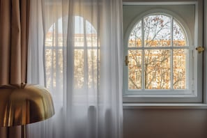 Una habitación con un amplio ventanal de arco, una lámpara y cortinas traslúcidas.
