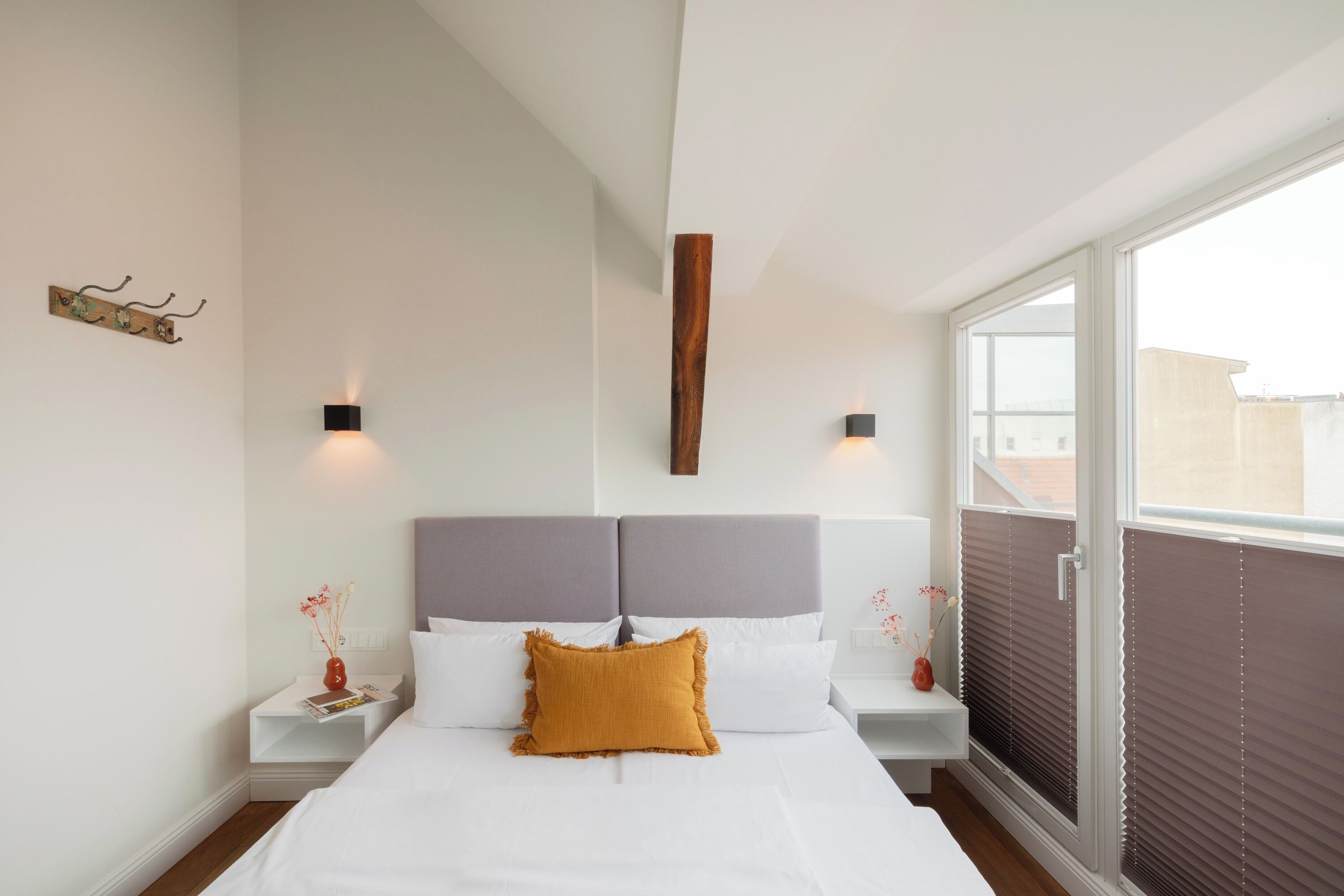 Ein Schlafzimmer mit einem großen Bett, zwei Nachttischen, einer Holzwand und einem Fenster mit Jalousien.