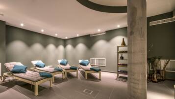 Experience relaxation in this serene spa room with four massage tables, a bookshelf, and a unique cylindrical column.