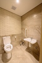 Un baño con inodoro, lavamanos y paredes de mármol.