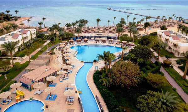 A resort with a large central pool, multiple smaller pools, and a beach area with umbrellas and lounge chairs. - Golden Beach Resort - All inclusive (Hurghada)