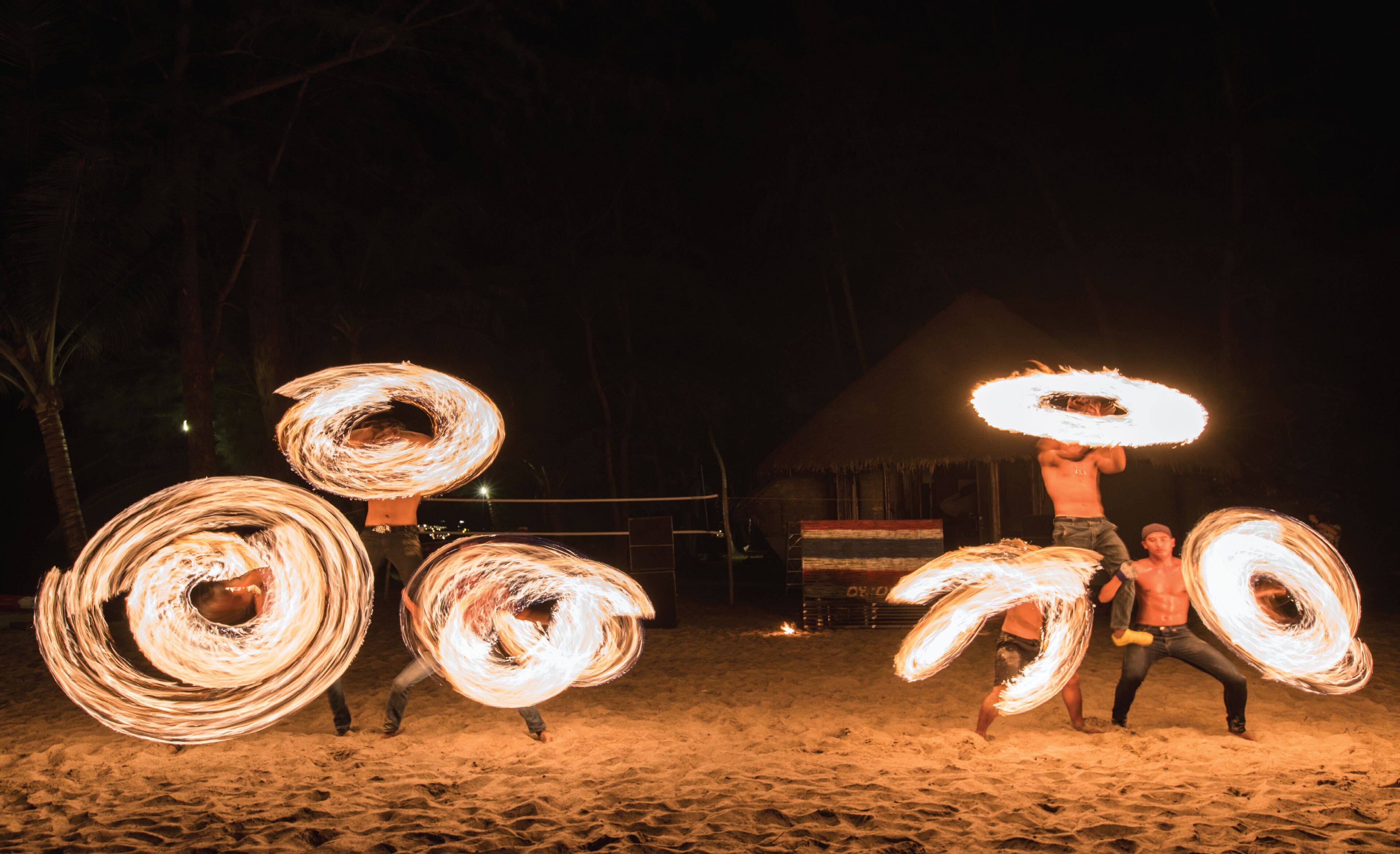A nighttime outdoor scene with people performing fire-based tricks.