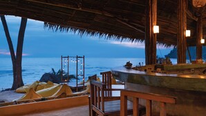 An outdoor seating area with wooden furniture and a view of the ocean. - Peter Pan Resort (Ko Kood)