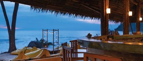 An outdoor seating area with wooden furniture and a view of the ocean.
