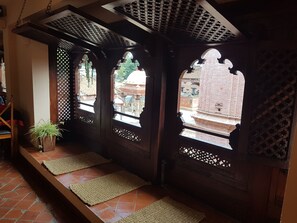 Una estructura de madera tradicional con elaboradas ventanas celosías y piso de baldosas.