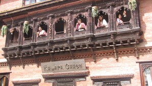 Un edificio tradicional con balcones de madera ornamentados y plantas colgantes.