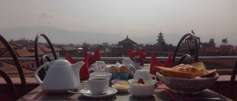 A table with breakfast items and a view of a pagoda and mountains.